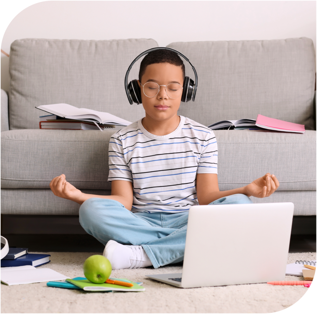 Junge mit Kopfhörern meditiert vor einem Laptop als Ausgleich zum digitalen Alltag.