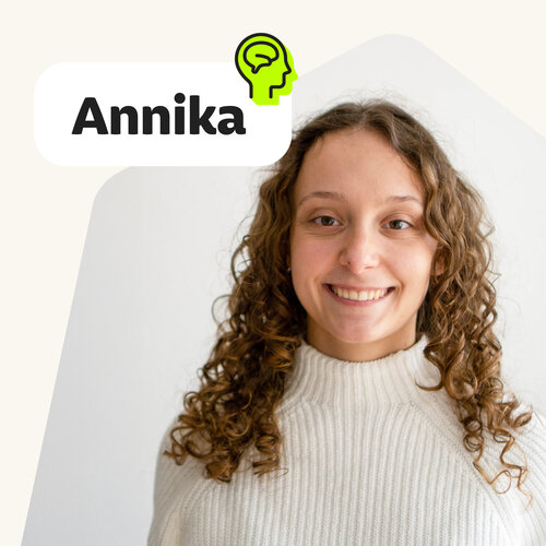 Porträt von Annika Nassal mit lockigen braunen Haaren, cremefarbener Strickpullover, Text „Annika“.