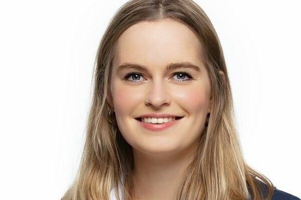 Anna-Lena Füllsack, Redakteurin, Porträt mit natürlichem Lächeln, braune Haare mit Highlights, dunkler Blazer