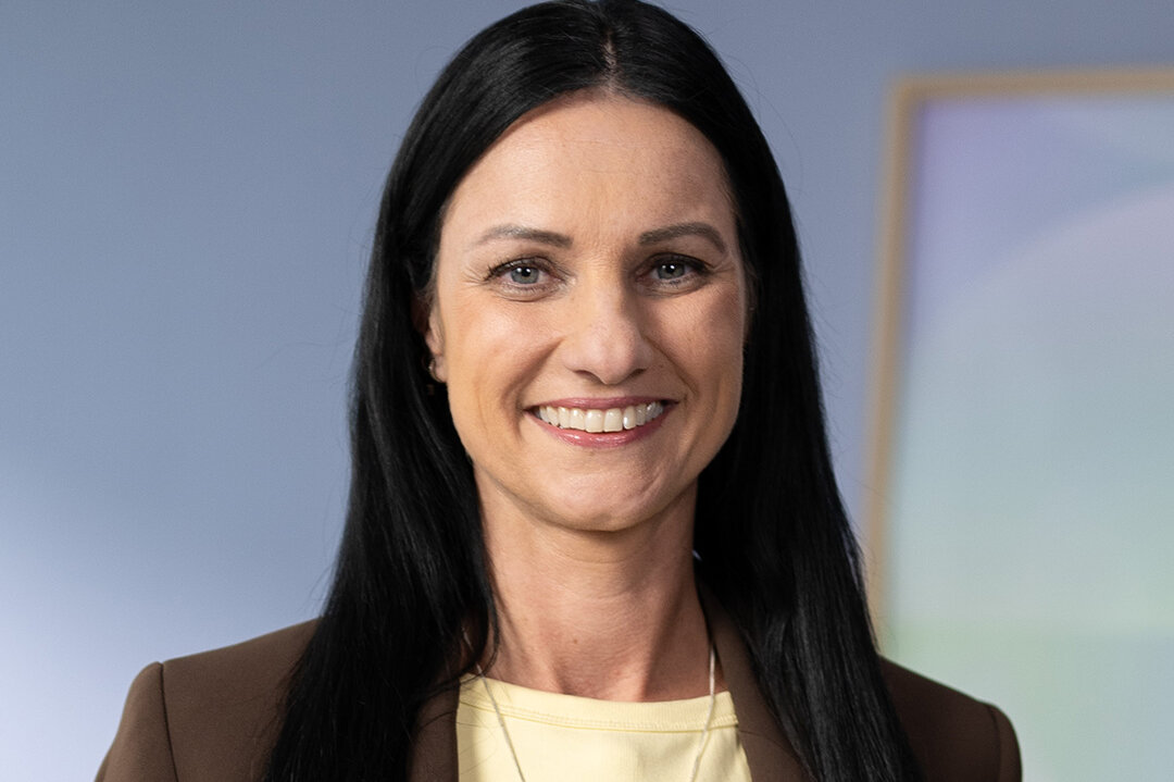 Kristin Van der Meer im braunen Blazer, gelbes Oberteil, Porträt vor hellem Hintergrund