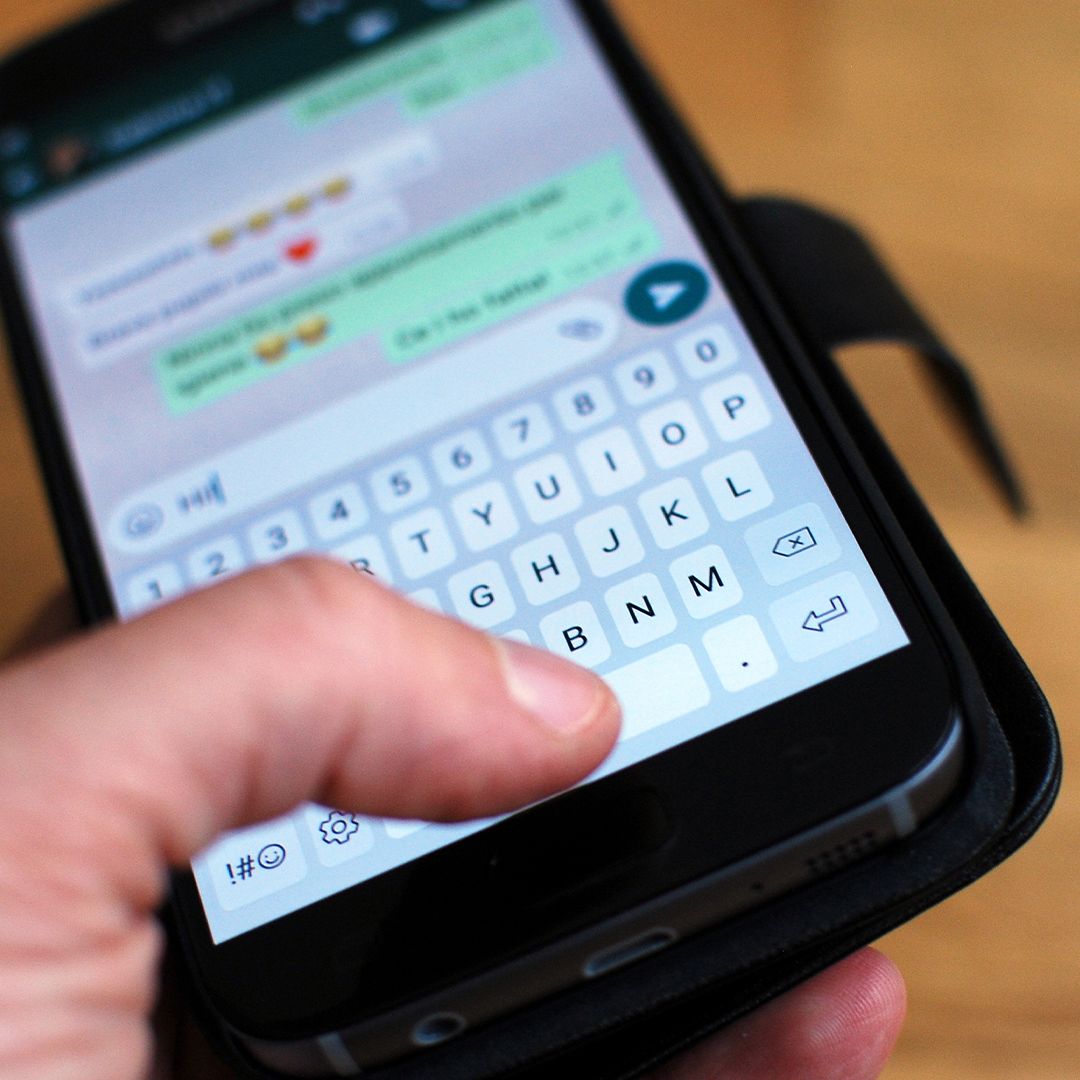 Hand hält ein Smartphone, auf dem ein geöffneter WhatsApp-Chat mit eingetippter Nachricht zu sehen ist. DGK_Artikel-08_Whatsapp-groupes.jpg