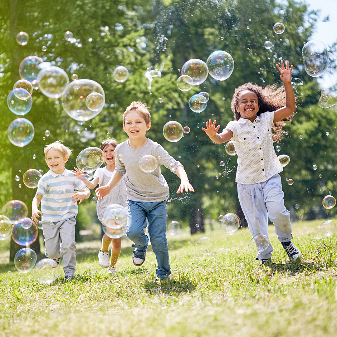 Vier Kinder rennen lachend über eine Wiese und spielen mit Seifenblasen. 20251215_DGK_Artikel-06_7Mind-Soft-Skills.jpg
