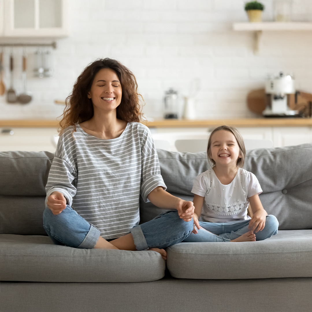 Mutter und Tochter praktizieren gemeinsam Achtsamkeit und Meditation zu Hause – beide sitzen entspannt im Schneidersitz auf dem Sofa mit geschlossenen Augen 20251215_DGK_Eltern_Artikel-15_7Mind-Mindful-Interactions-within-the-family.jpg