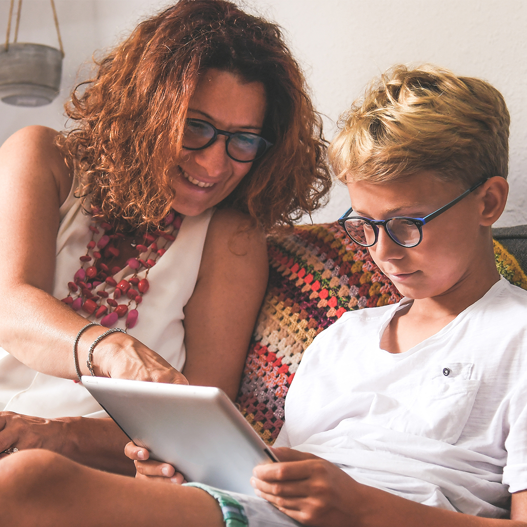 Frau mit Laptop zeigt Junge etwas auf Tablet DGK_Beitraege_Eltern_Digital_und_Gesund_E_B1-header.jpg