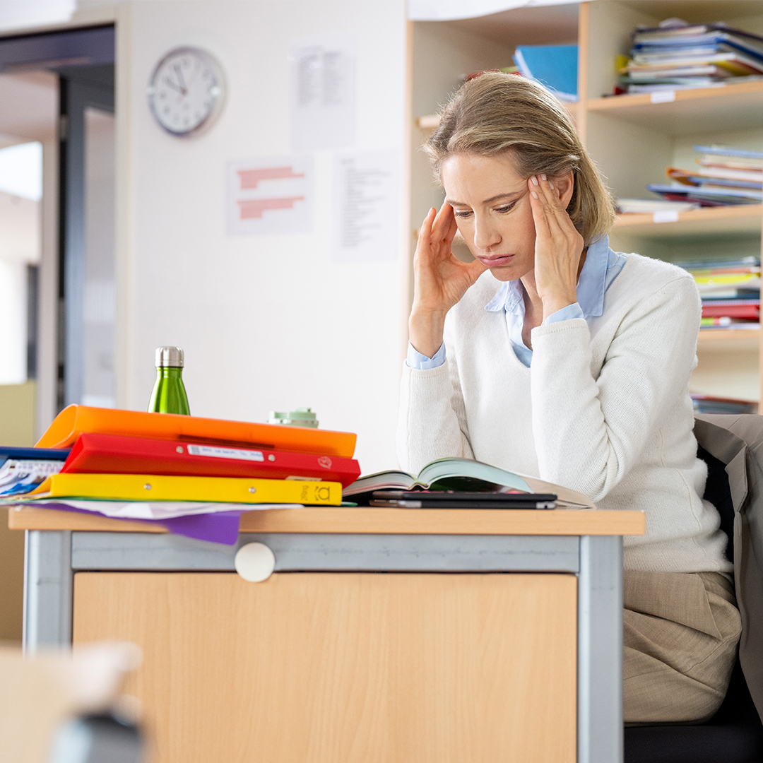 Lehrerin an Pult reibt sich die Schläfen DGK_Blog_09_3x-7-Miles-header.jpg