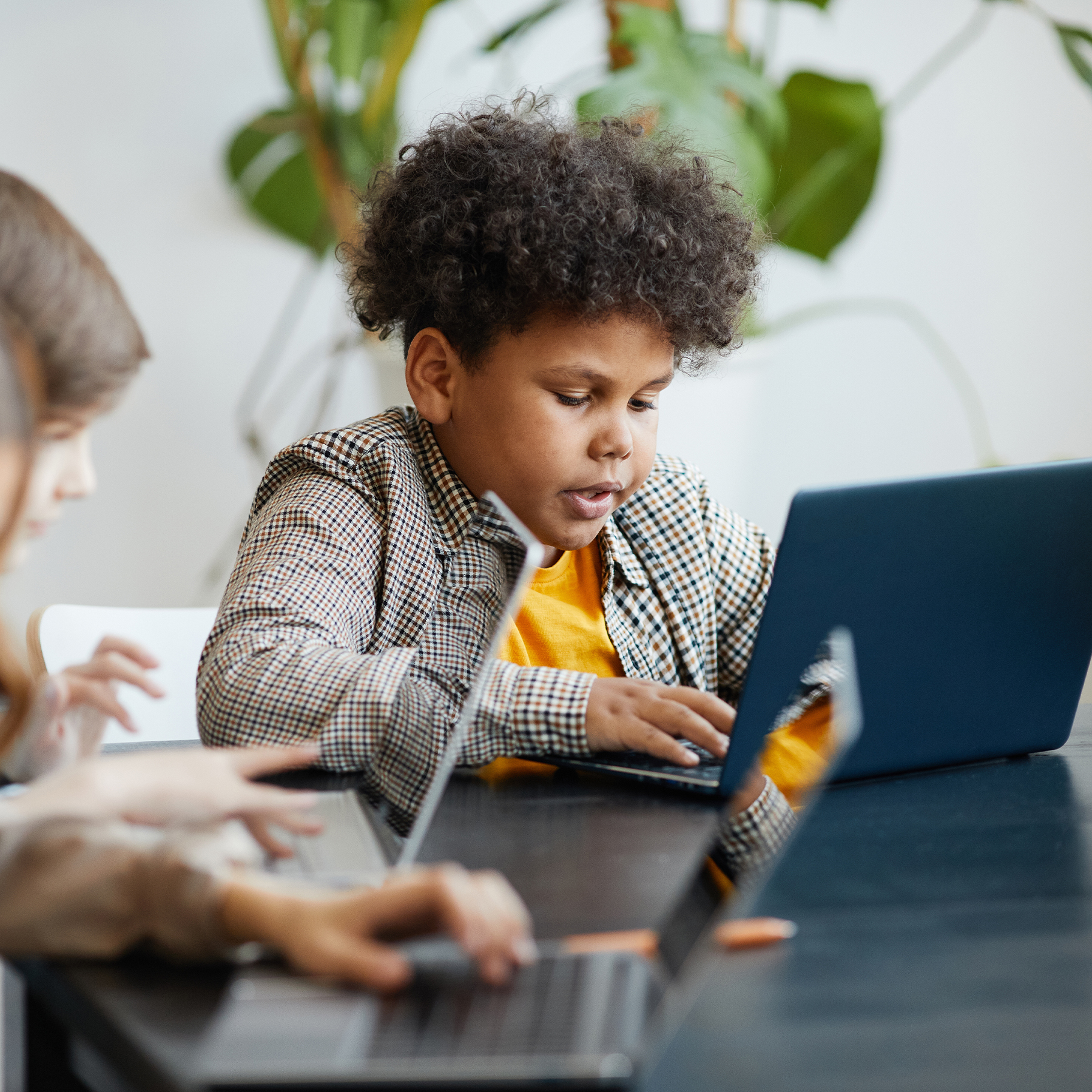 Schüler mit Afro-Frisur konzentriert am dunkelblauen Laptop, digitales Lernen, KI-Kompetenz entwickeln