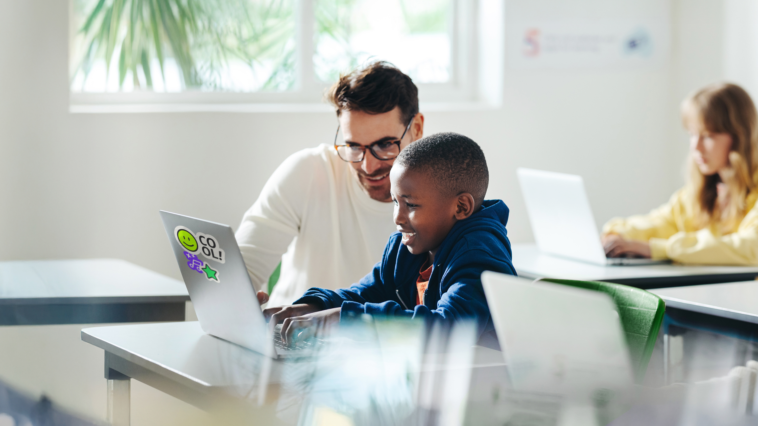  Erwachsener unterstützt Kind am Laptop beim Erlernen digitaler Kompetenzen