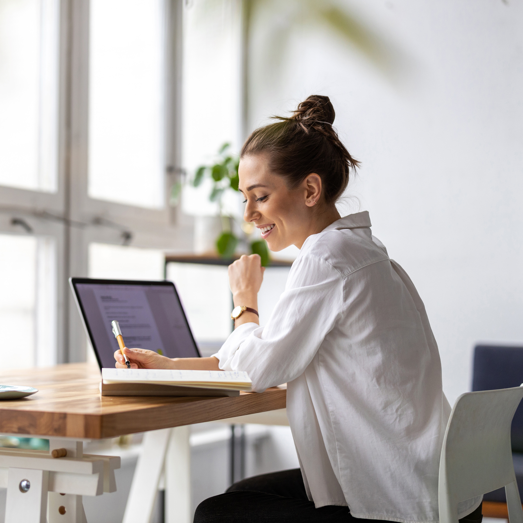 Frau arbeitet konzentriert am Laptop, macht Notizen, Selbstcheck-Prozess, modernes Homeoffice